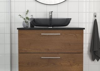 A wooden bathroom vanity with a glass countertop sink