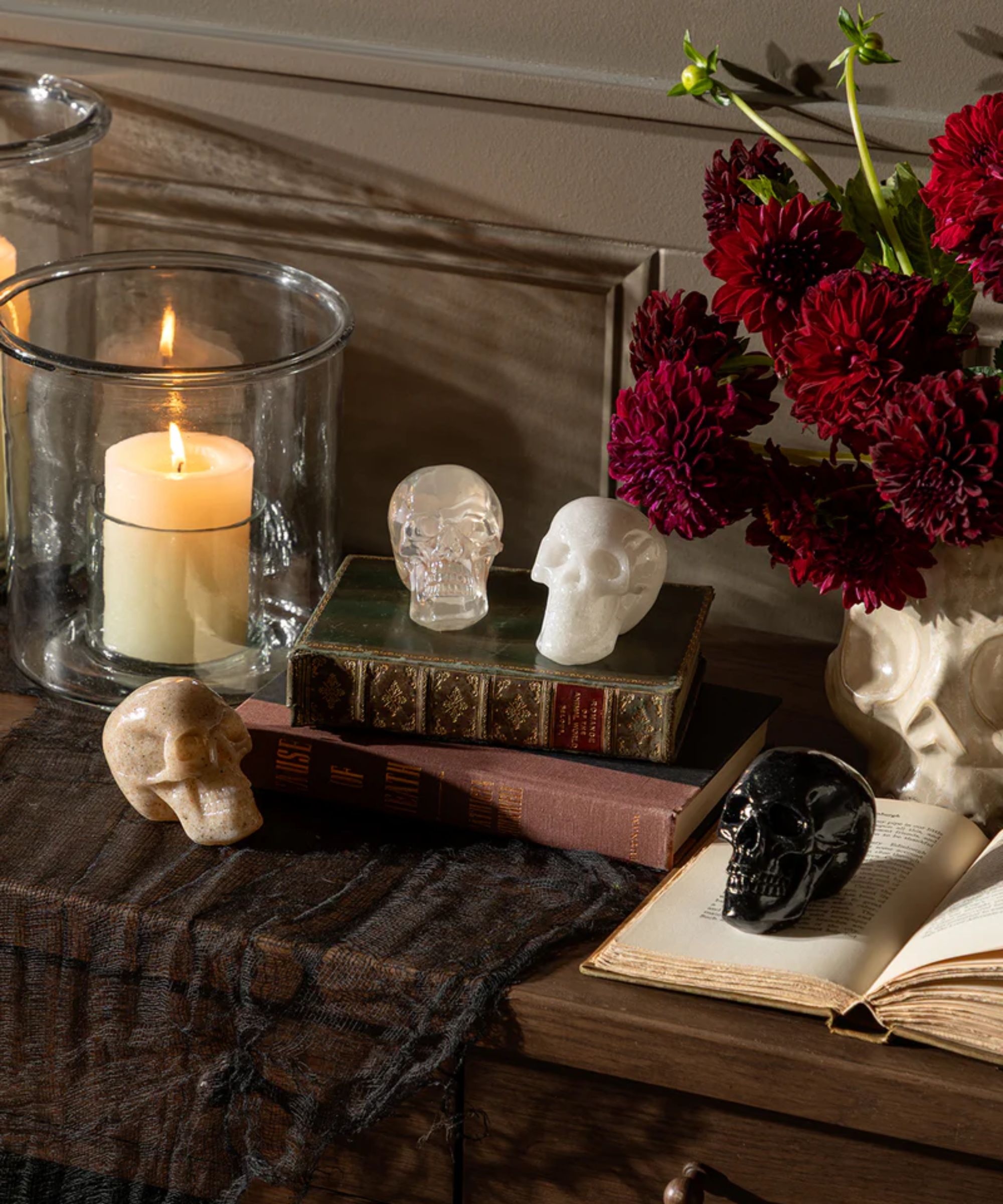Sideboard with black lace runner, resin skulls, pillar candle and red dahlias