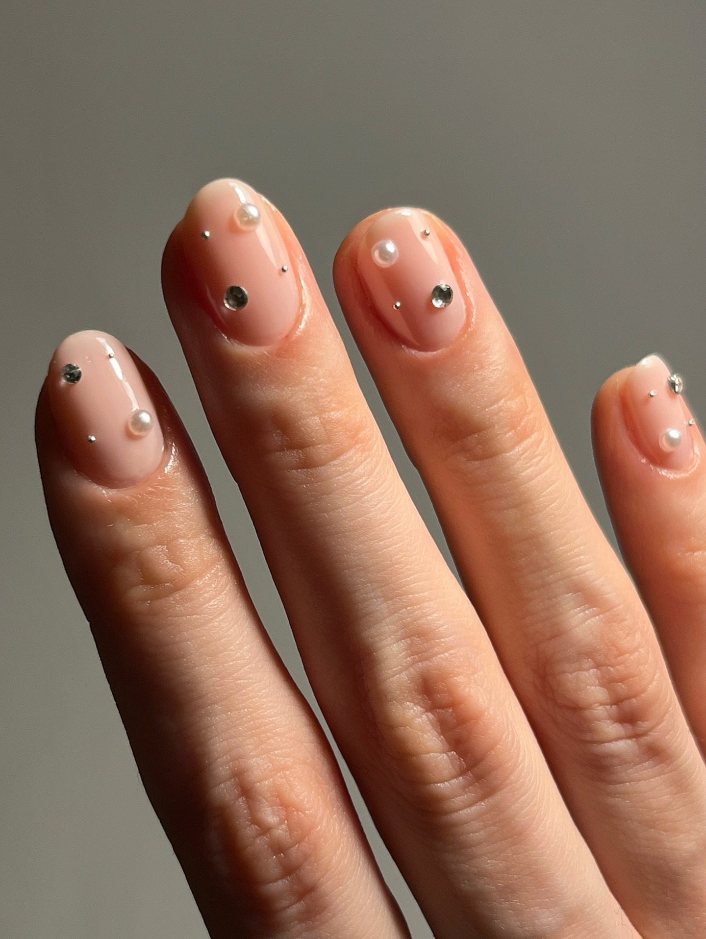 A clear manicure with stud and pearl detailing
