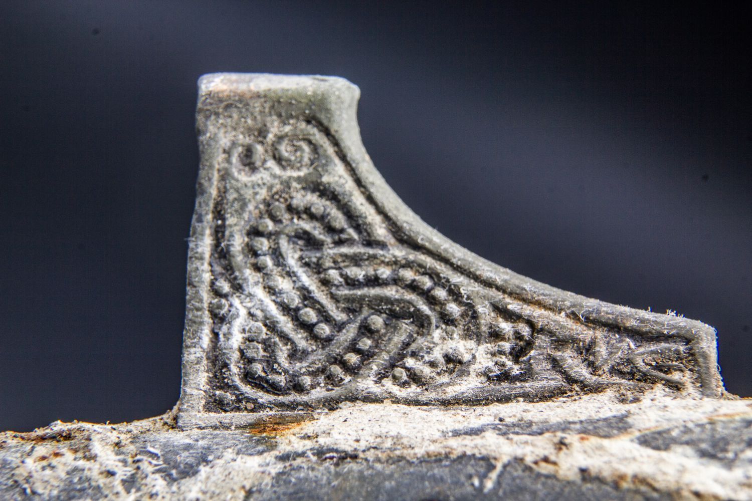 A close-up photograph of a pattern on the ornately detailed spearhead.