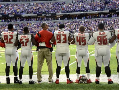 Tampa Bay Buccaneers players link arms during the national anthem before a game.