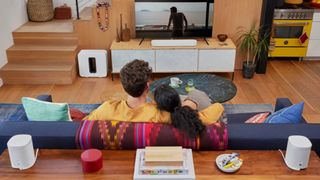 Ett par som tittar på tv med flera sonos-högtalare