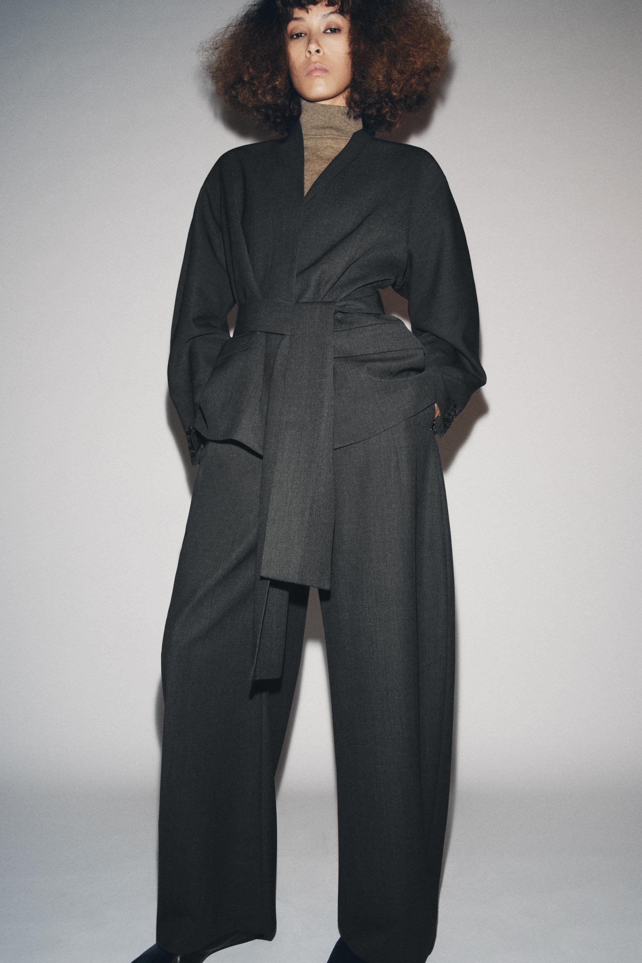model wears matchign kimono blazer and balloon pants with tan sweater layered under and black square toe flats