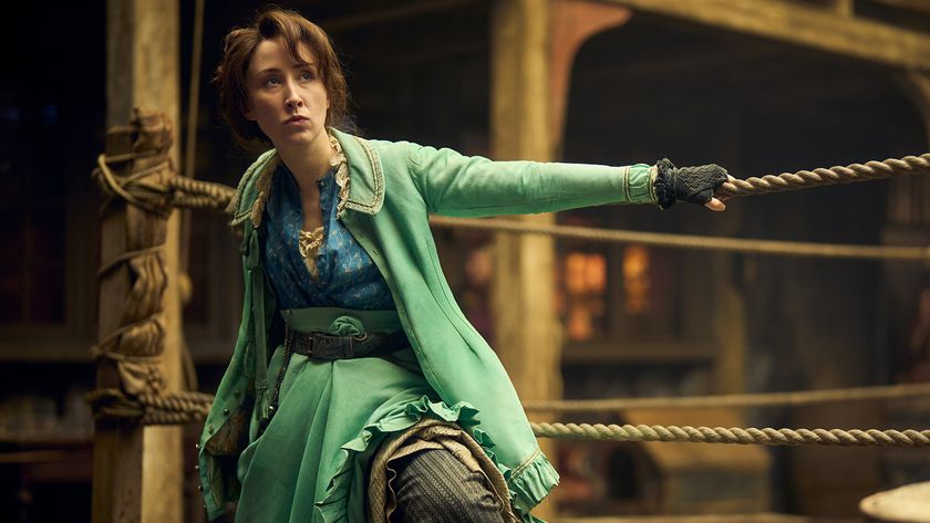 A woman wearing a Victorian dress leans on the ropes of a boxing ring