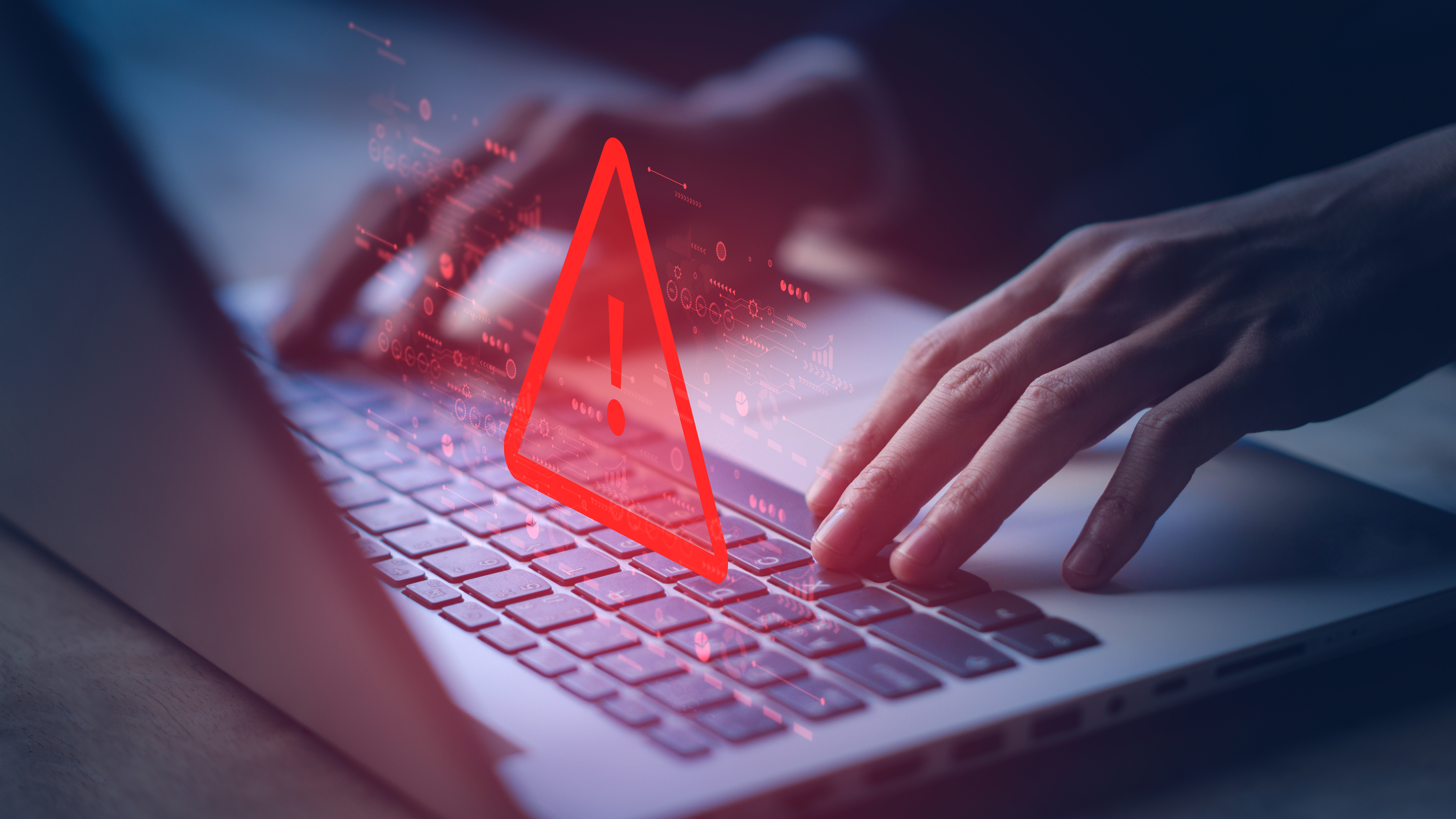 Two hands typing on a laptop keyboard with a warning exclamation mark above it