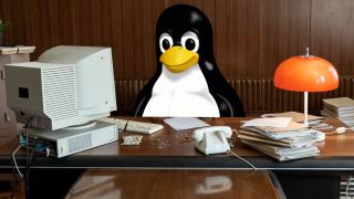 Tux the penguin at a desk using an old computer