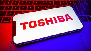 The Toshiba logo on a smartphone lying on a laptop