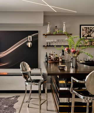 A home bar with silver chairs and a black and gold island