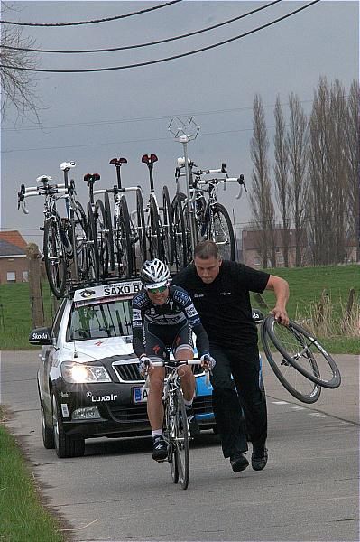 A Saxobank rider has a wheel change before rejoining the action
