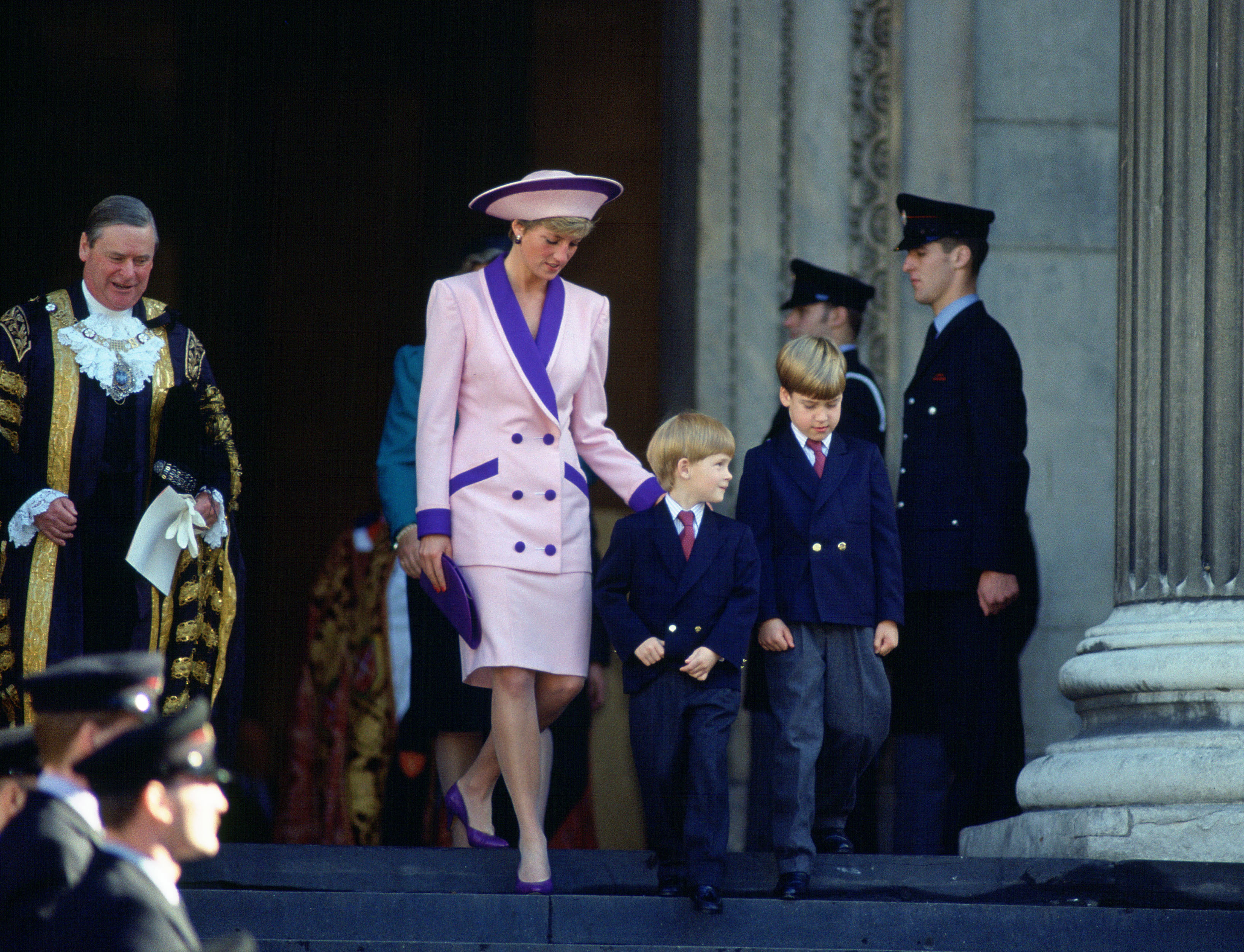 Princess Diana wearing a purple suit and hat walking outside of St Paul&#039;s Cathedral with Prince William and Prince Harry