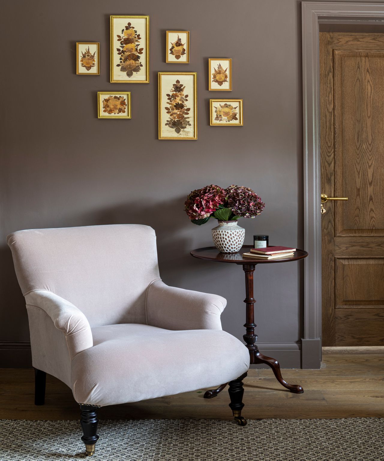 room with mauve brown walls, cream velvet armchair, patterned rug and dark wood occasional side table
