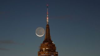 A crescent moon is shown next to the Empire State Building.