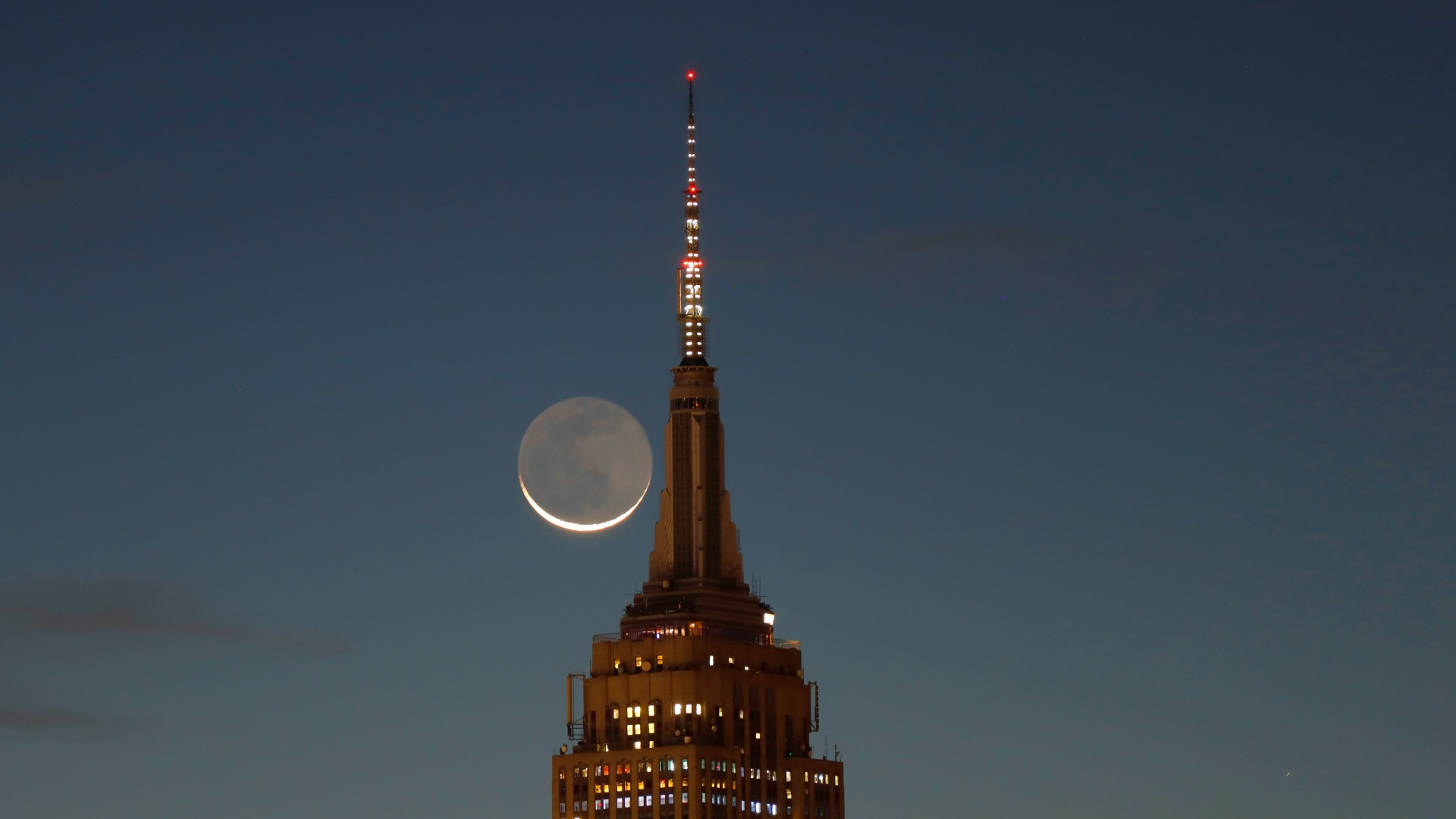 A crescent moon is shown next to the Empire State Building.
