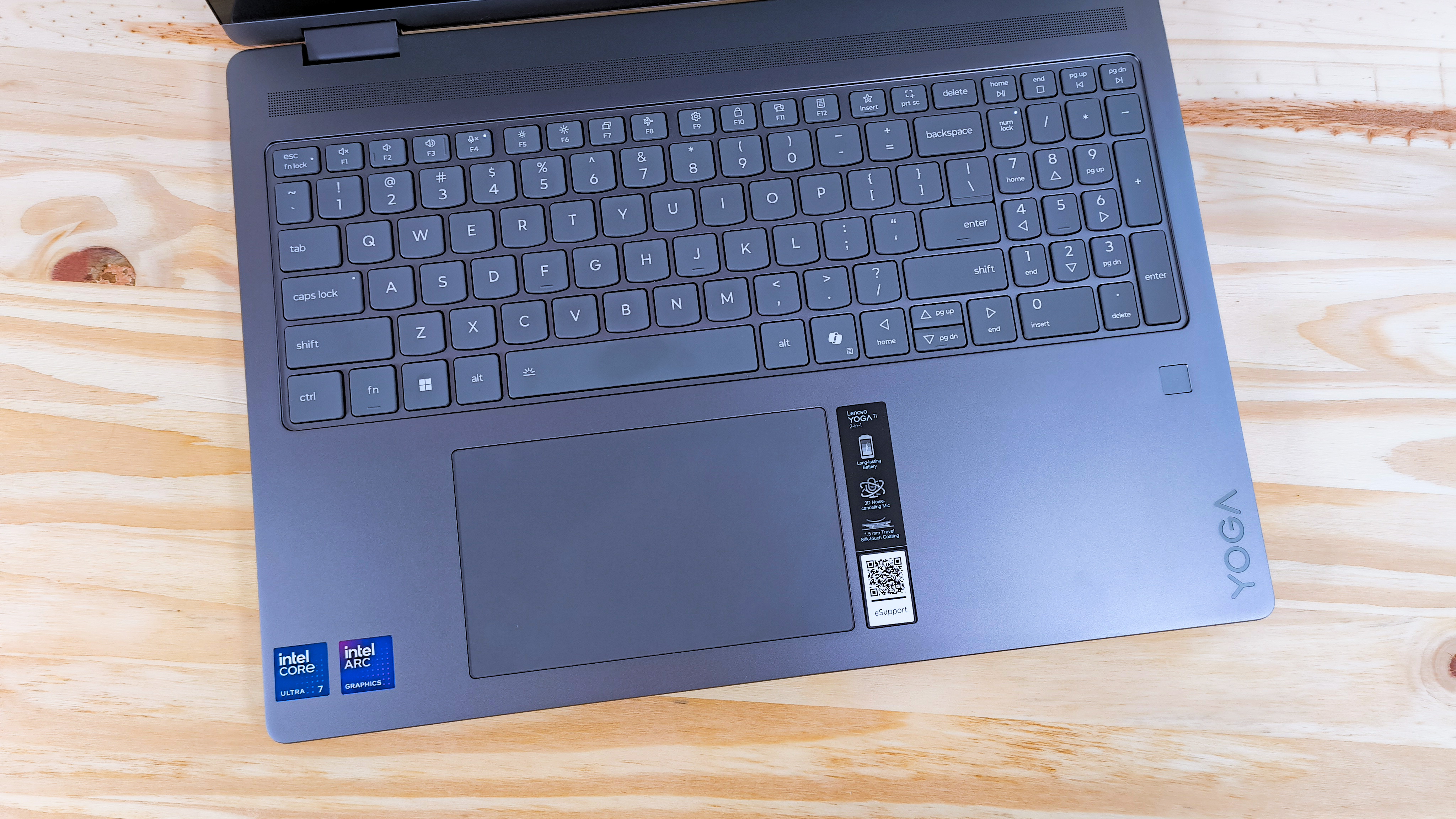 The keyboard deck on the Lenovo Yoga 7i 2-in-1 16 seen from above on a wood table