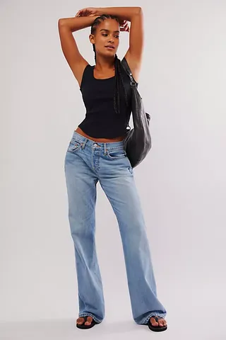 A model wears a black tank top with Re/done Loose Boot Jeans and black thong sandals