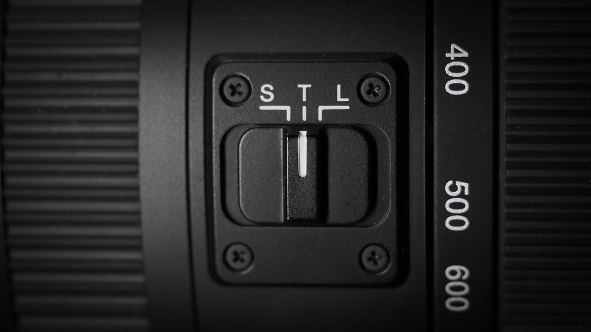 OM System M.Zuiko 150-600mm f/5.0-6.3 IS lens, mounted to an OM System OM-1 Mark II, on a wooden surface lit with moody lighting