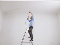 man changing a ceiling light fixture
