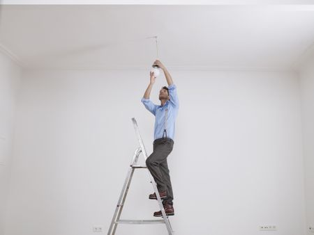 man changing a ceiling light fixture