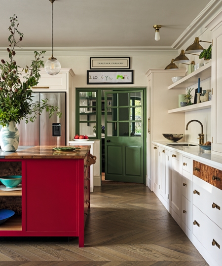 a kitchen with a red kitchen island, white cabinets, open shelves, and a green pantry door
