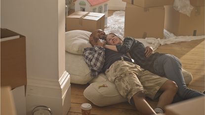 A young couple relax together among moving boxes after moving in together.