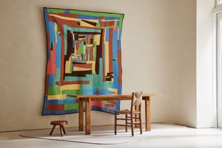 Colourful textile artwork by Loretta Pettway Bennett with wooden table, stool and chair by Charlotte Perriand