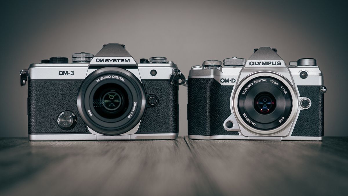 OM System OM-3 and Olympus OM-D E-M5 Mark III cameras on a wooden surface