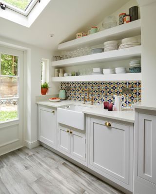A small kitchen idea with cream/white shaker style cabinetry, butlers sink, belfast sink, butler's sink and open shelving