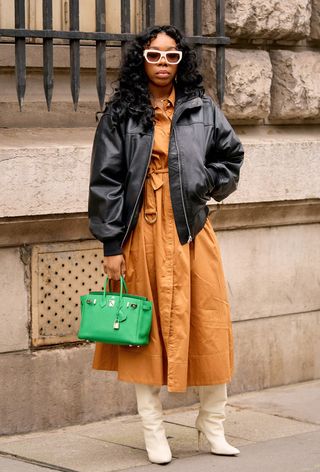 a street-style photo of a woman carrying a Hermés bag in a story about how to buy an hermés bag