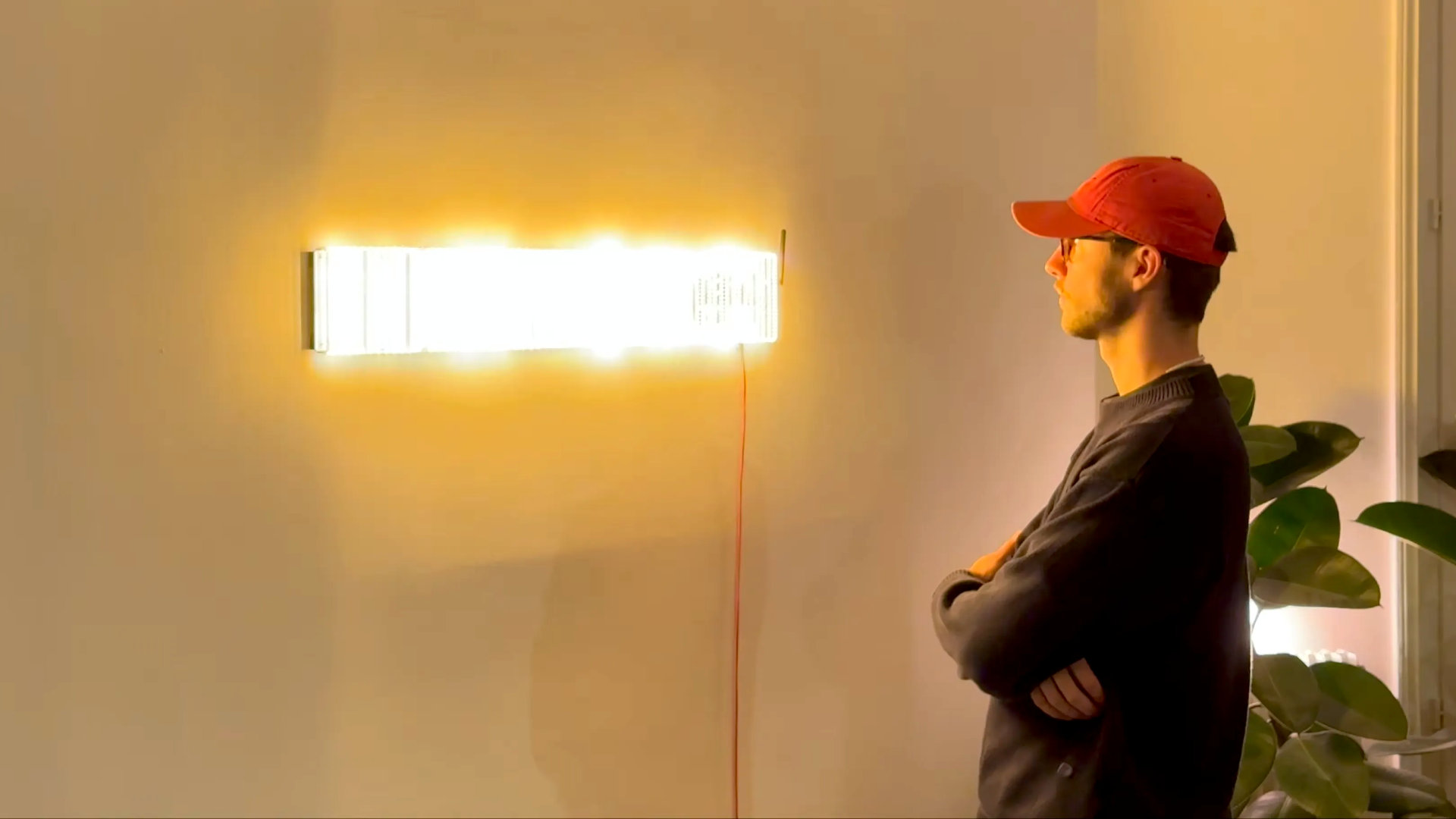 A photograph of an engineering art sculpture called Spectrum Slit, with its creator Rootkid stood next it, showing how it translates radio wave signals into light