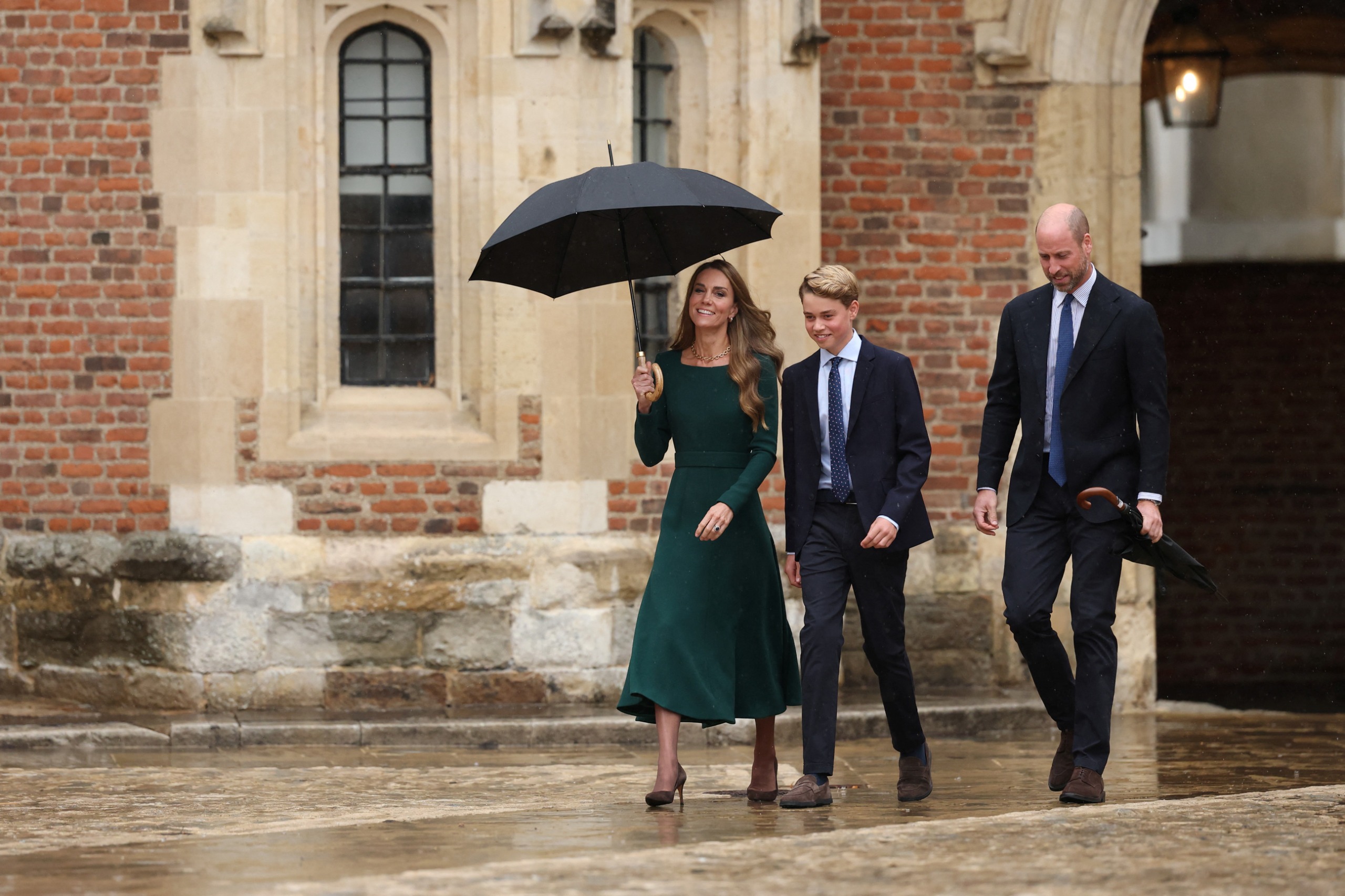 Princess kate, Prince George and Prince William walking with umbrellas outside Eton College