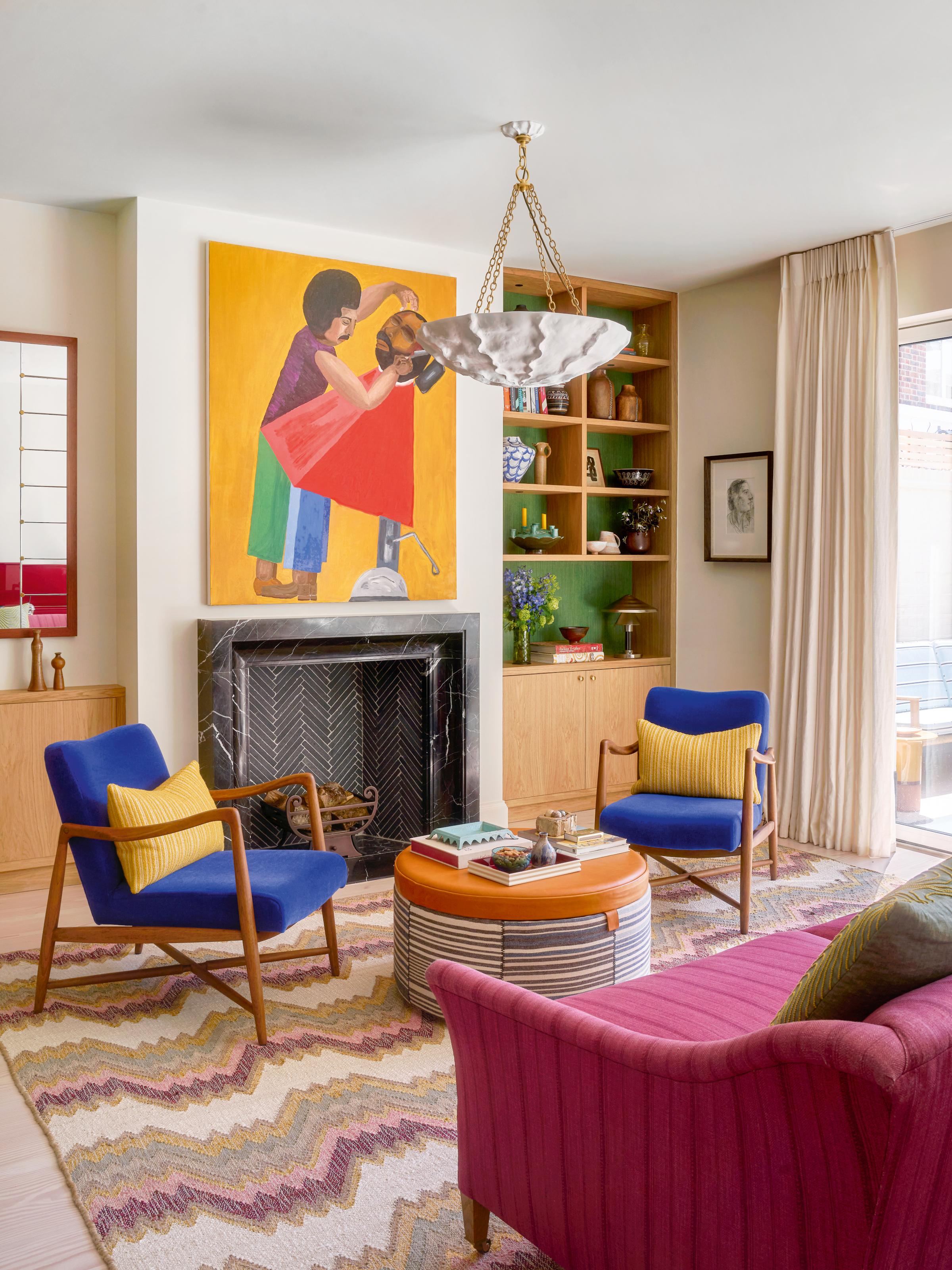 Living area with figurative yellow print, geometric rug, blue and wood armchairs and orange coffee tables