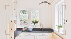 small cream kitchen with black countertops and a wooden ceiling clothes airer to save space