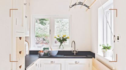 small cream kitchen with black countertops and a wooden ceiling clothes airer to save space