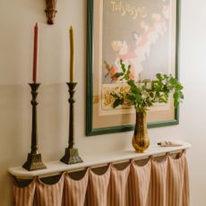 hallway with fabric radiator cover and shelf, candles, vase, framed poster 