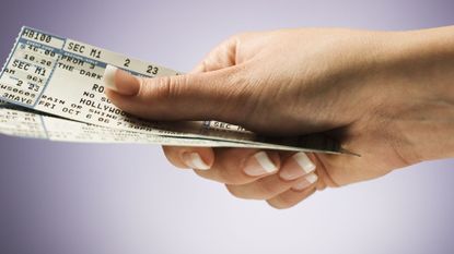 woman with concert tickets in hand