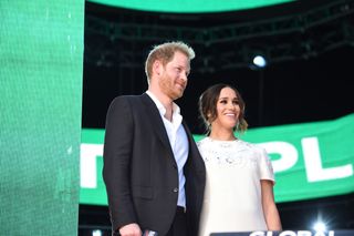 Prince Harry and Meghan Markle stand close to one another on stage