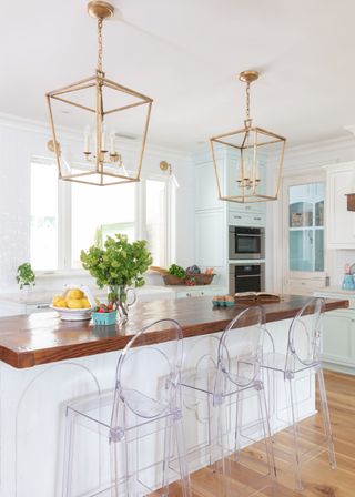 white kitchen with kitchen island, breakfast bar, gold lantern pendants, ghost bar stools