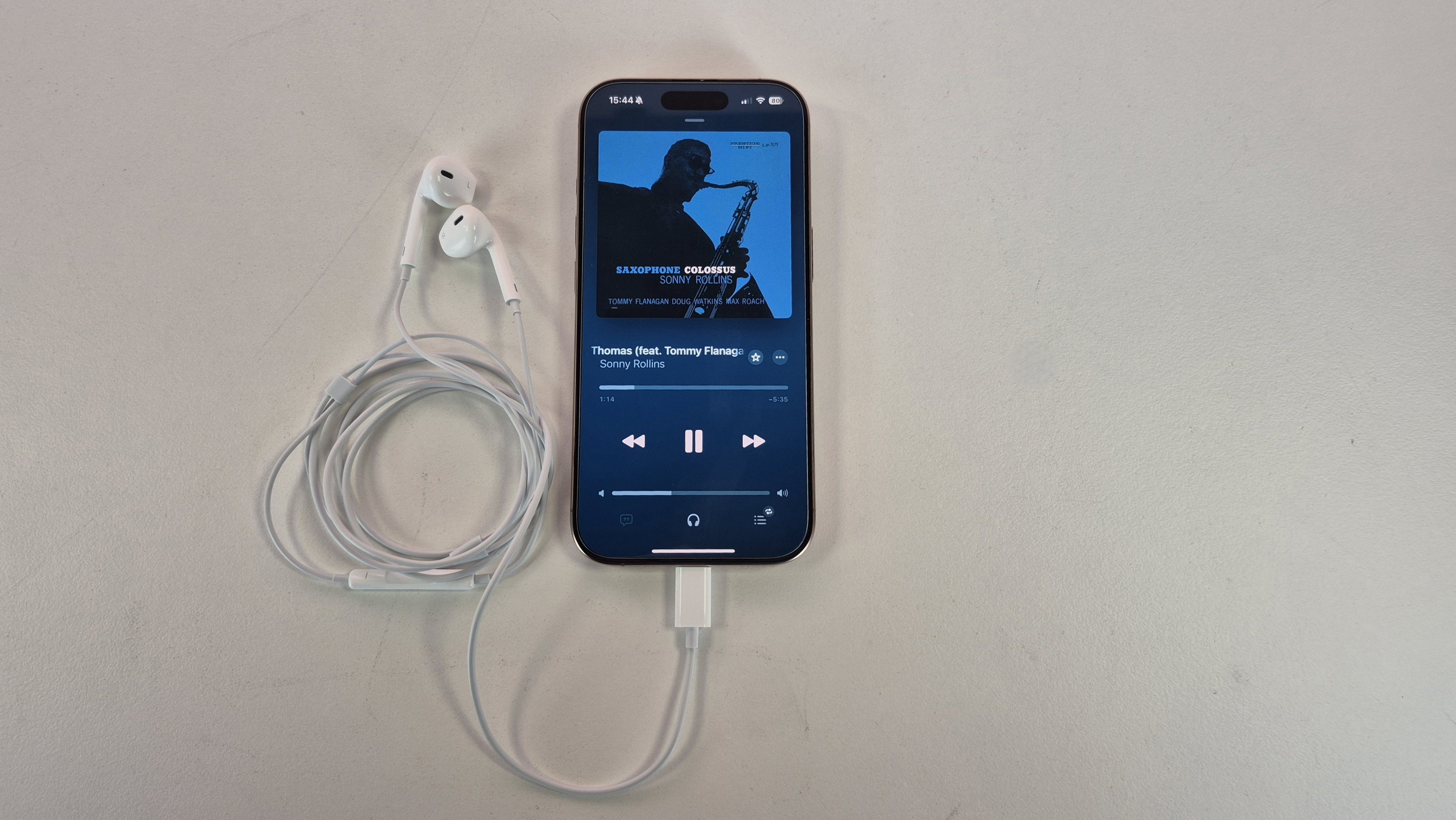 Apple EarPods USB-C plugged into iPhone 16 with Apple Music showing on the handset's display