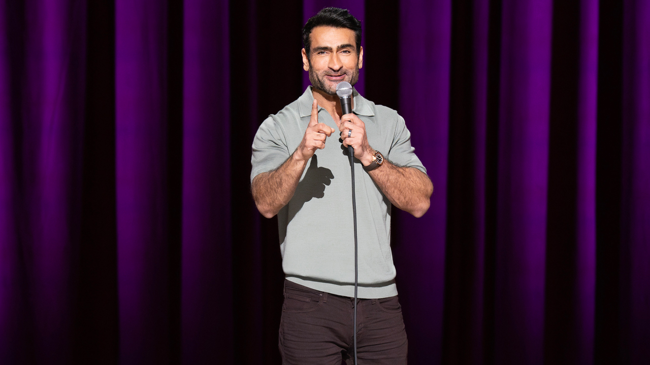 Kumail Nanjiani on stage in front of a purple curtain in Night Thoughts