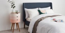 Scandinavian furniture in a bedroom with a navy bed and pink modular bedside table