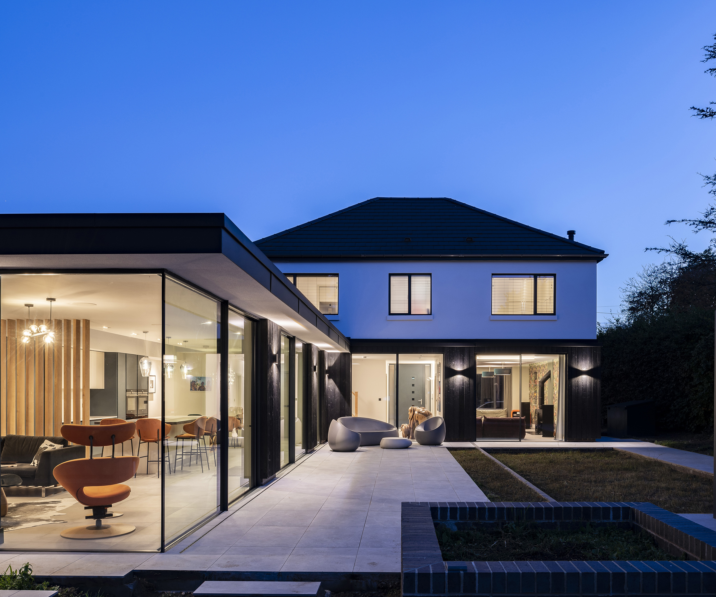 A newly renovated and extended 1930s detached home at dusk with interior and exterior lighting