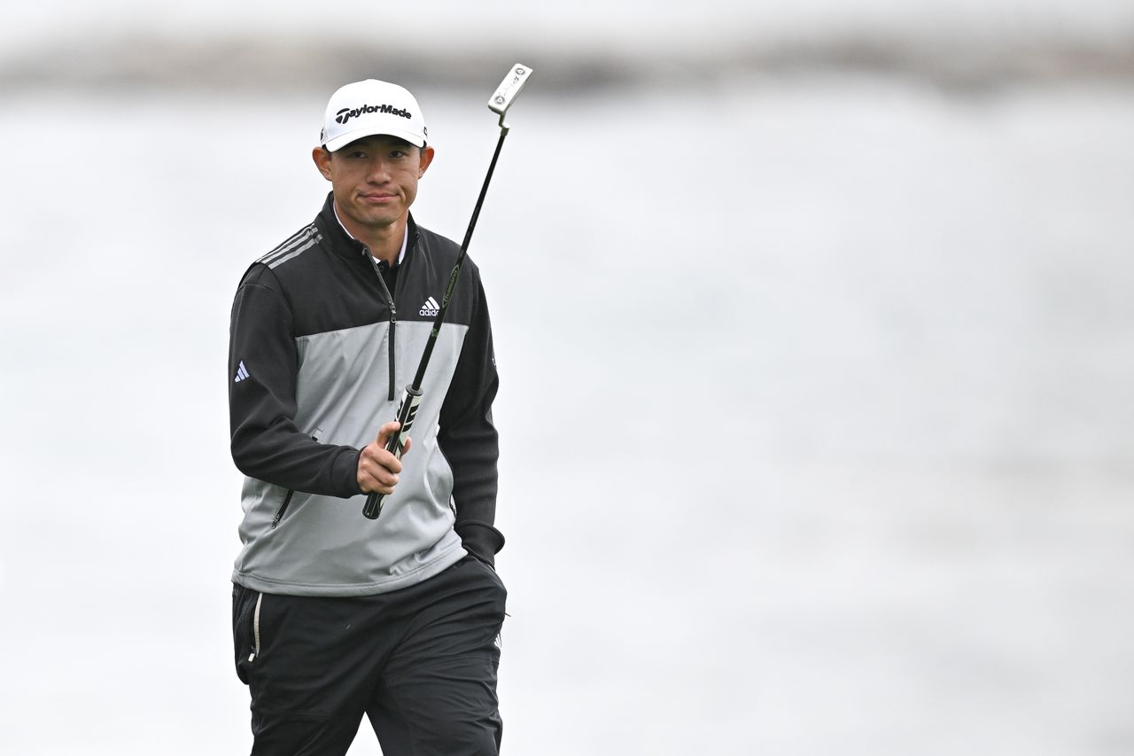 Collin Morikawa raises his putter in the air