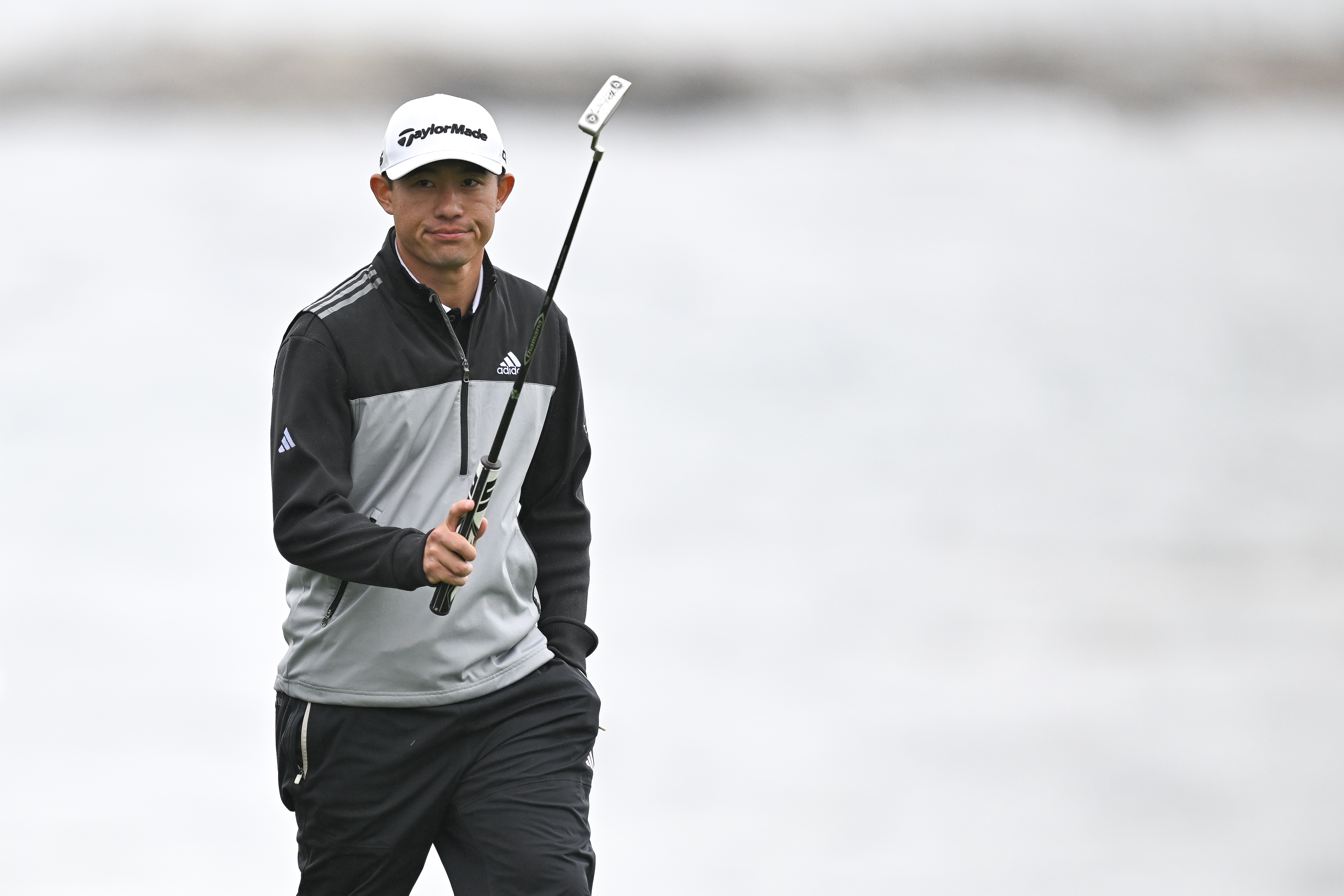 Collin Morikawa raises his putter in the air