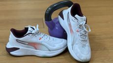 A pair of Puma PWR hybrid shoes on a wooden floor, with a kettlebell in the background.