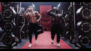 two bodybuilders walking in a gym drinking protein shakes