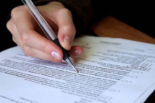 Person reviewing contract with pen in hand