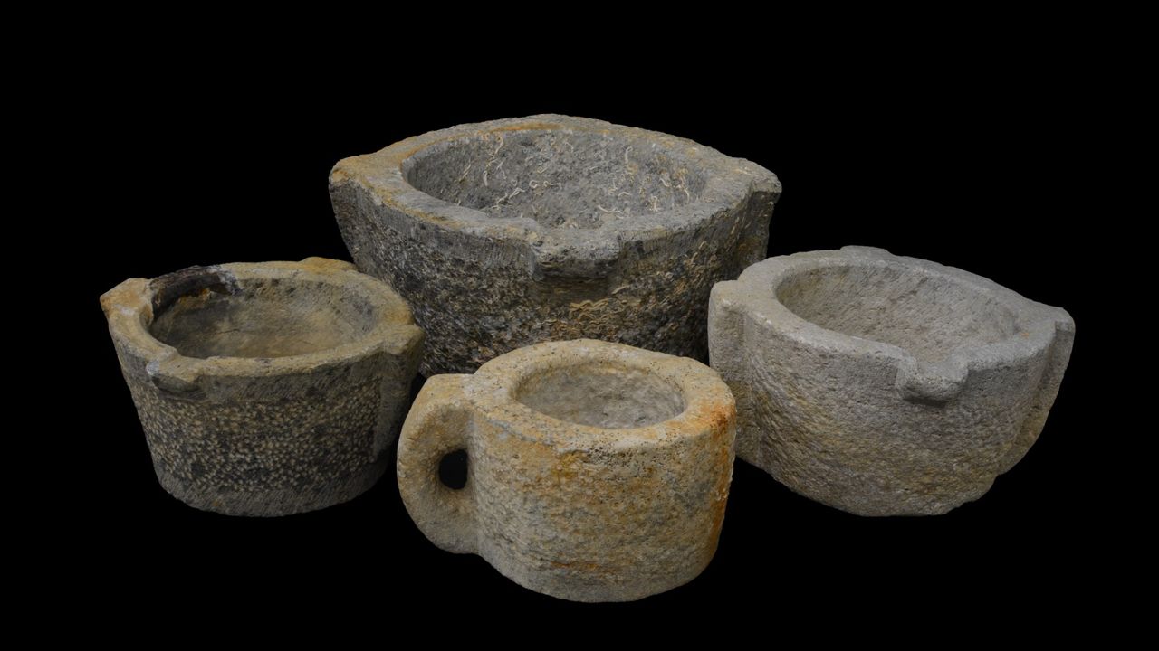 Three stone mortars (vessels used for grinding) and a stone cup. They look very worn as they have been lost in the ocean for a long time.