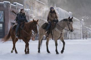 bella ramsey as ellie and isabela merced riding on horses through a snowy town in the last of us season 2