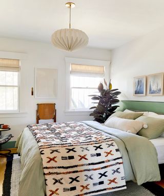 Small bedroom with neutral walls, green bedding and patterned throw