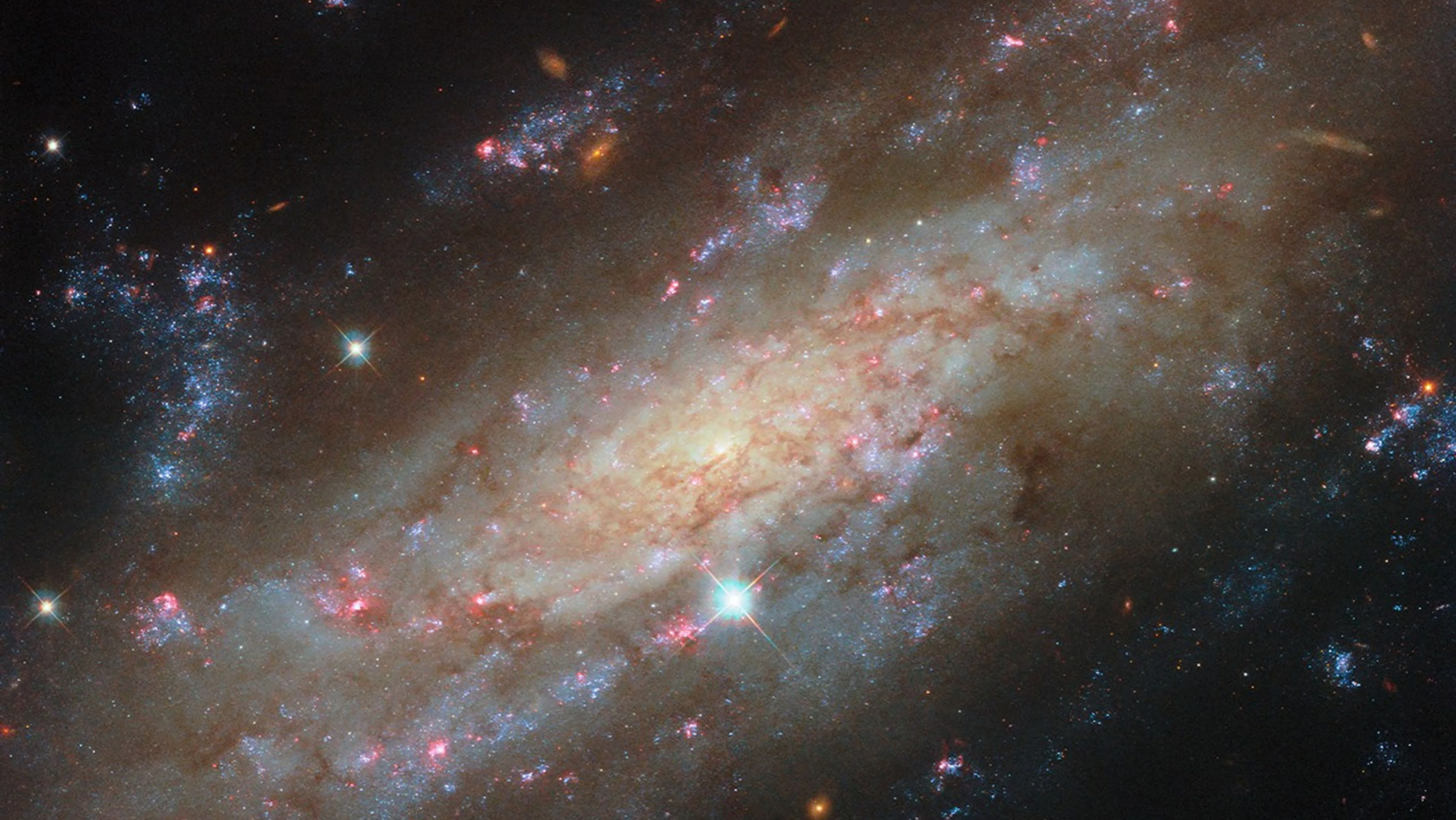 A galaxy glittering with stars and blue and red gas clouds.